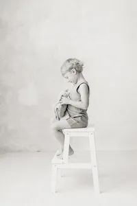 A black and white photo of a little boy and his stuffed toy during his mothers maternity session taken in a Dallas/Fort Worth photography studio.