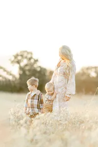 A mother standing in a Dallas/Fort Worth park with her two young boys standing close.