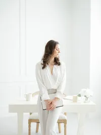 Photo of a business owner sitting on her desk holding her notebook as she looks down over her shoulder.