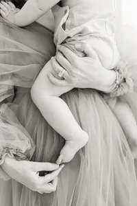Black and white photo of a mother playing with her babies toes for an in studio photography session.