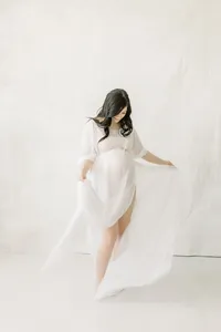 A photo taken for a maternity session in a Dallas/Fort Worth area photography studio of an expecting mother while she is dancing playfully around the studio.
