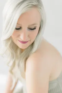 Close up photo of a woman wearing beige lace lingerie as she looks over her shoulder and smiles at a DFW photography studio.