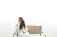 Photo of a woman sitting on a bench in a Dallas photography studio as she looks down and smiles.