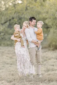 A beautiful family of 4 portrait taken while they are standing together in a field at a local Fort Worth park taken by a family photographer in Dallas TX.