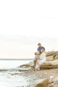 Family photo of them all sitting on a large rock by a Dallas Fort Worth lake for their family photos.