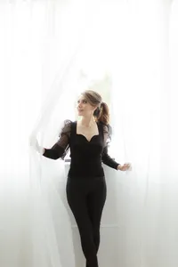 Photo of a beautiful woman dressed in all black as she plays in the sheer drapes of a Dallas photography studio.