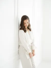 Local Dallas business owner leaning against the wall in a Dallas photography studio as she holds books and loos down.