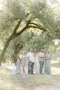 A Dallas family photo taken while they are posing close together in the middle of a path at a local Dallas/Fort Worth park for their family portrait session.