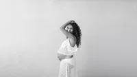 Expecting mother in a flowing gown posing for a Dallas maternity portrait session