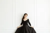 Photo of a woman dressed in a black off the shoulder gown as she playfully dances in a Dallas/Fort Worth photography studio for her boudoir photos.