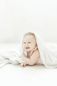 Baby girl playing around under a blanket for her mommy and me session with her mother at a Frisco photography studio.