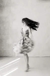 A beautiful black and white photo of a woman dancing in the middle of a Dallas photography studio for her boudoir session.