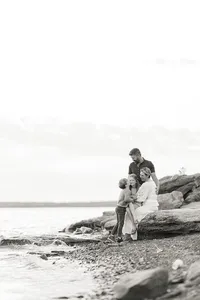A beautiful black and white family photo as they are posing on rocks at a local DFW lake for their photographer.