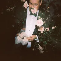 Film double exposure of groom holding a bridal accessory surrounded by roses.