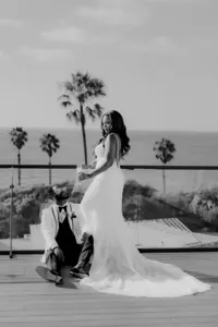 Groom looking up at bride on balcony in San Diego with ocean in the back