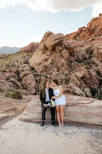 Engaged couple sitting on rock at the Red Rock Canyon smiling