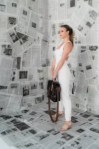 A woman poses in front of newspapers
