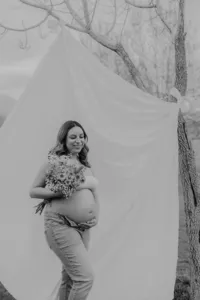A woman looks down while holding her pregnant belly