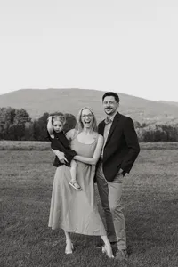 Jess and Corey Combs smiling holding their daughterin Manchester, Vermont