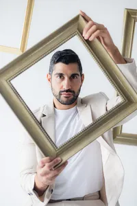 A man sits on a stool surrounded by frames