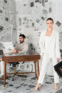 A couple is at a desk with a newspaper background
