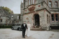 Bride and groom walking with castle in background in Ireland