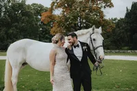 Bride looking at groom holding the reigns of a white horse