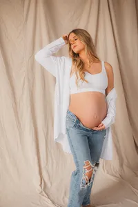 A pregnant woman stands while holding her stomach