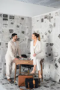 A couple talks over a desk surrounded by newspapers