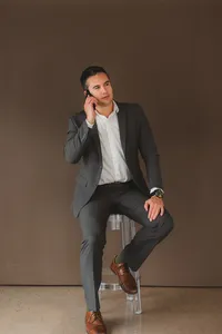 A man sits on a stool on the phone
