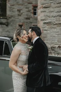 Groom holding his bride laughing with retro car in the background at The Castle in Leslie, Ireland
