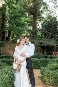 Groom holding pregnant wife's stomach