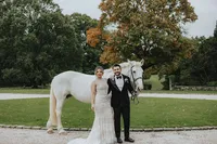 Bride and groom in front of a white horse for their Ireland wedding