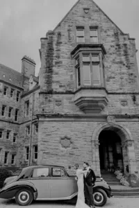 Bride hugging groom in front of a retro car in front of an Ireland castle