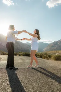 Engaged couple dancing on empty road with Nevada mountains in the back