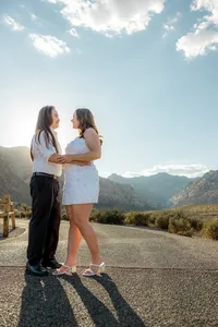 Engaged couple smiling on empty road with Nevada mountains in the back