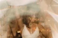 A blurred, artistic shot of a woman dancing, possibly the bride, with light flares and soft focus