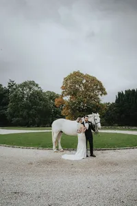 Bride looking at husband in front of white horse