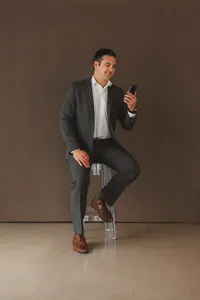 A man sits on a stool on the phone