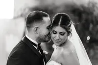 In a close-up, the groom leans in towards his bride, who gazes down softly, both savoring a peaceful moment together in black-and-white.