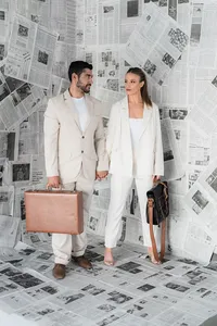 A couple holds bags in front of a newspaper wall