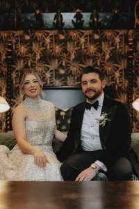 Bride and groom smiling with funky wallpaper in the back