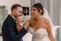 The newlyweds, beaming with happiness, toast each other with cocktails after their wedding ceremony, the bride in her lace gown and veil.