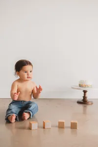 A kid sits next to blocks.