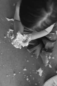 View from above of a child holding cake in his hands.