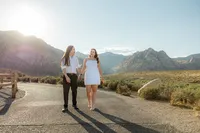 Engaged couple walking on empty road with Nevada mountains in the back