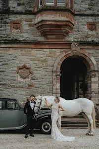 Bride and groom posing with horse and car in front of Ireland castle