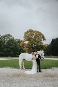 Bride looking at husband in front of white horse