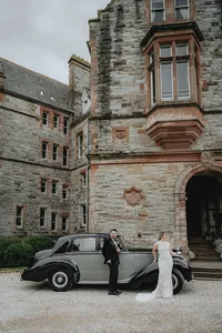Bride and groom leaning against old car in Ireland