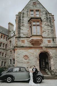 Bride and groom hugging in front of retro car in Ireland